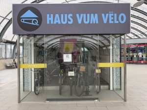 The Haus vum Vëlo entrance in Belval, with bicycles behind the glass under the blue sign