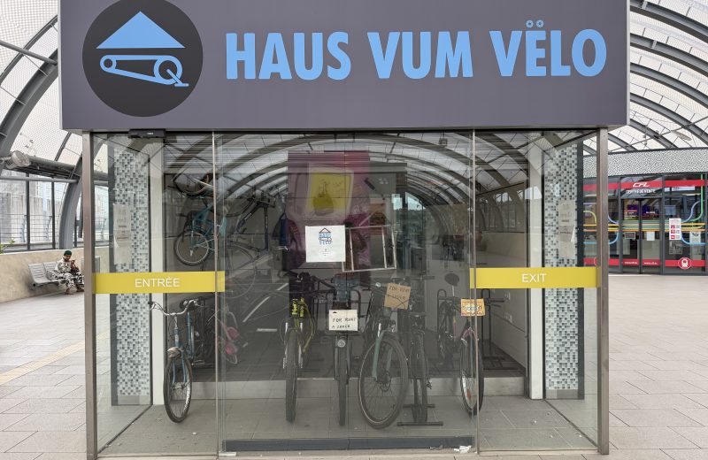 The Haus vum Vëlo entrance in Belval, with bicycles behind the glass under the blue sign
