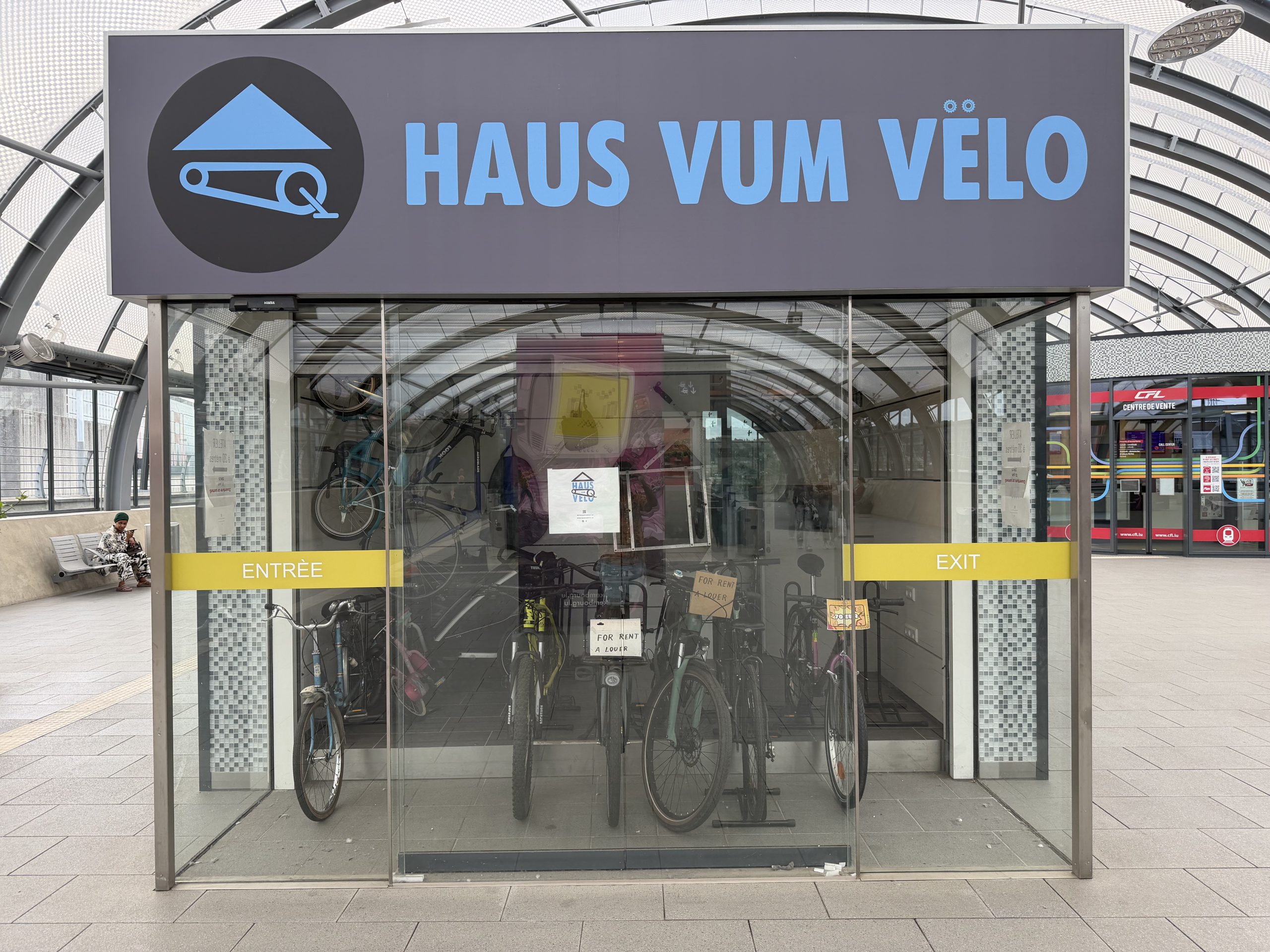 The Haus vum Vëlo entrance in Belval, with bicycles behind the glass under the blue sign