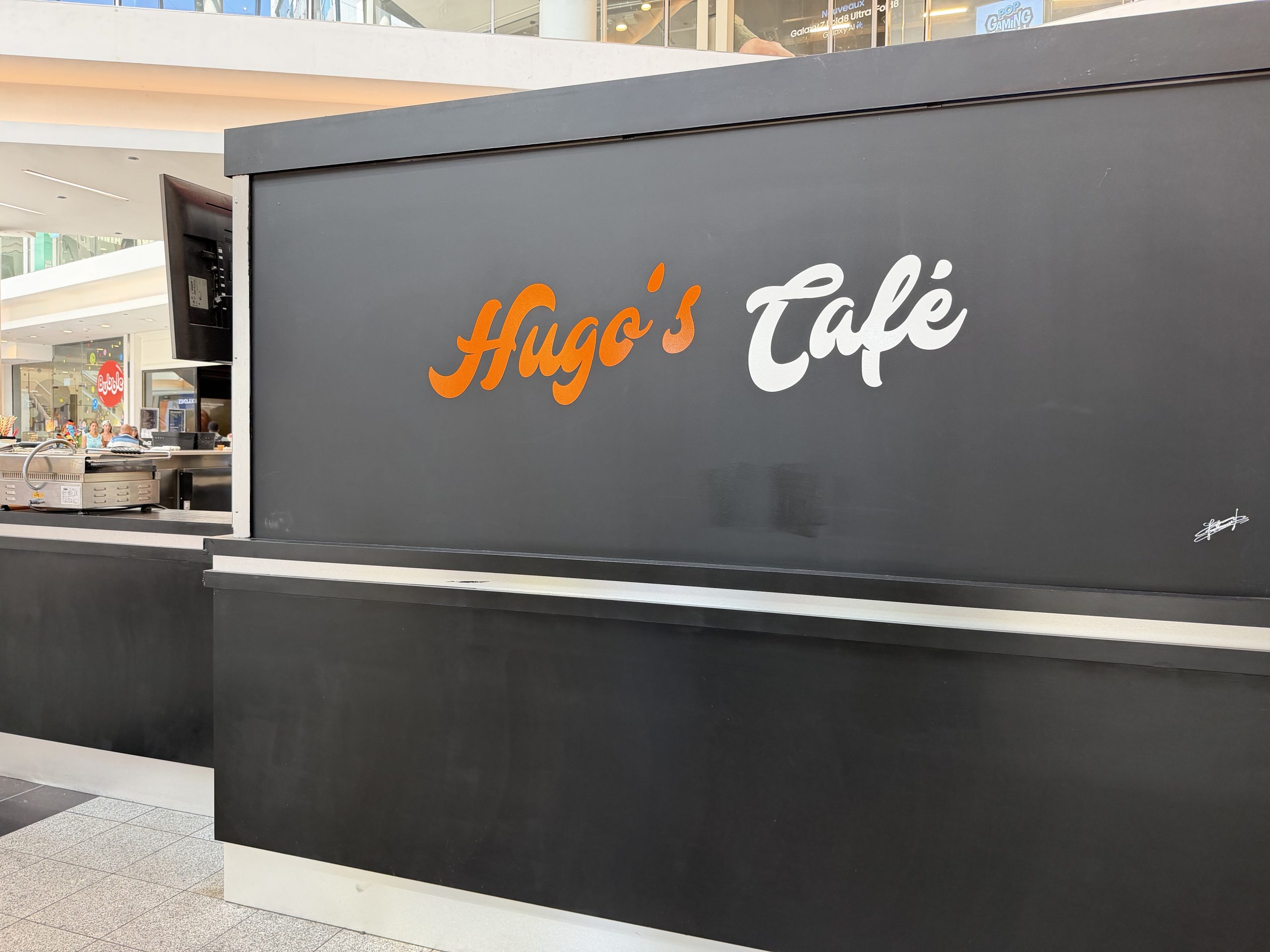 Hugo’s Café kiosk and seating area inside Belval Plaza