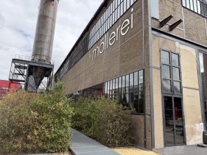 The Möllerei building in Belval, with its name along the facade and the chimney behind