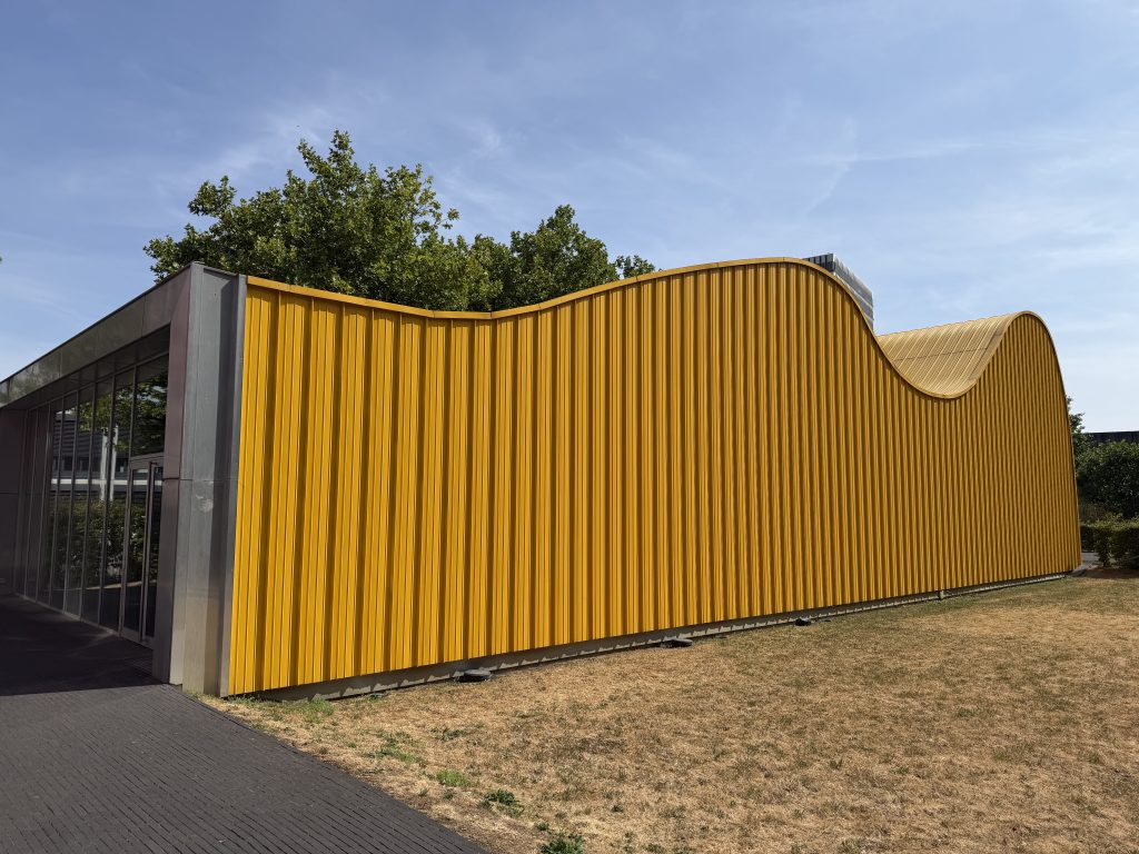 The yellow Skip Pavilion in Belval, its curved metal skin seen from the grass