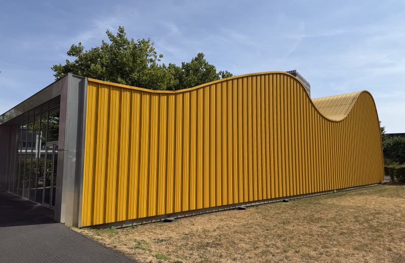 The yellow Skip Pavilion in Belval, its curved metal skin seen from the grass
