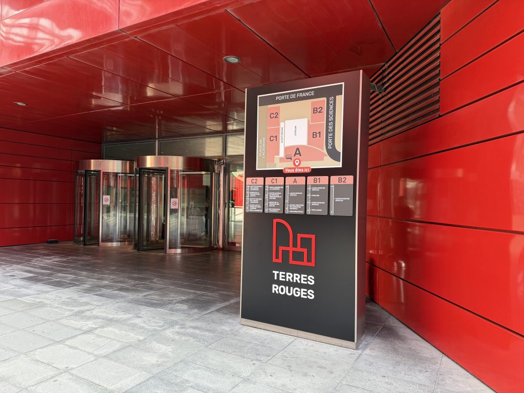 The red facade and entrance of the Terres Rouges Building at Porte de France