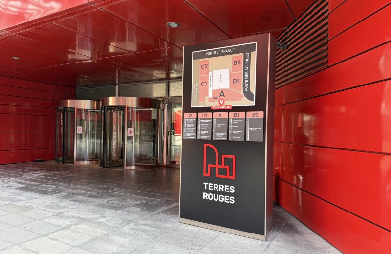The red facade and entrance of the Terres Rouges Building at Porte de France