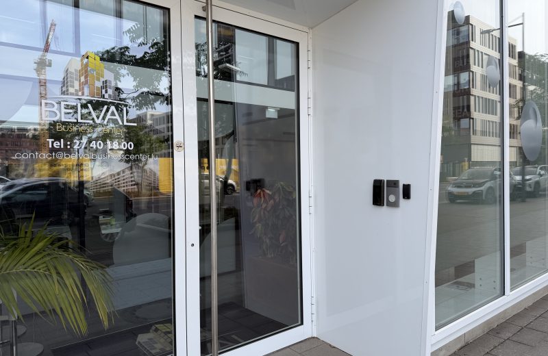 The entrance to Belval Business Center at 11 boulevard du Jazz, with the company name and contact details on the glass door and an intercom beside it.