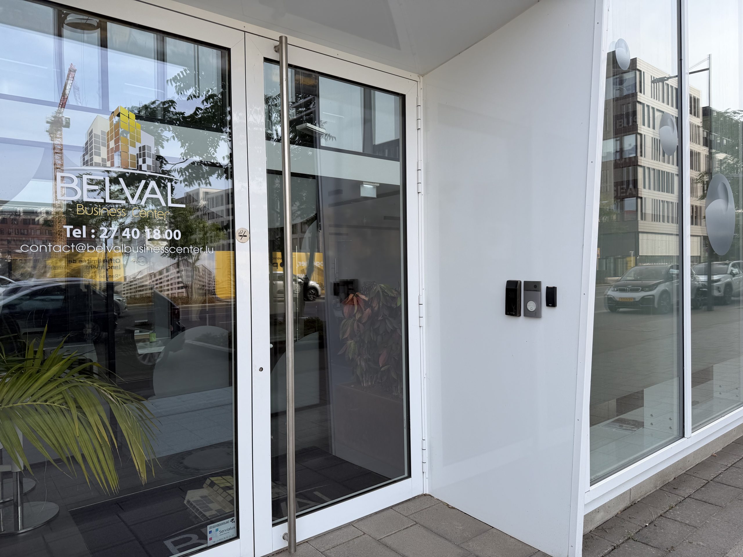 The entrance to Belval Business Center at 11 boulevard du Jazz, with the company name and contact details on the glass door and an intercom beside it.