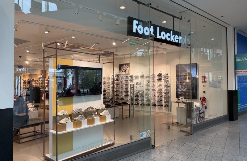 The Foot Locker shopfront in Belval Plaza, with the black Foot Locker sign above the entrance and rows of trainers displayed on the wall inside, footlocker.eu printed on the glass.