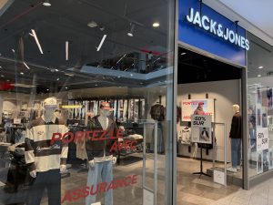 The Jack & Jones shopfront in Belval Plaza, with the blue Jack & Jones sign above the entrance and mannequins dressed in rugby shirts, denim jackets and caps in the window.