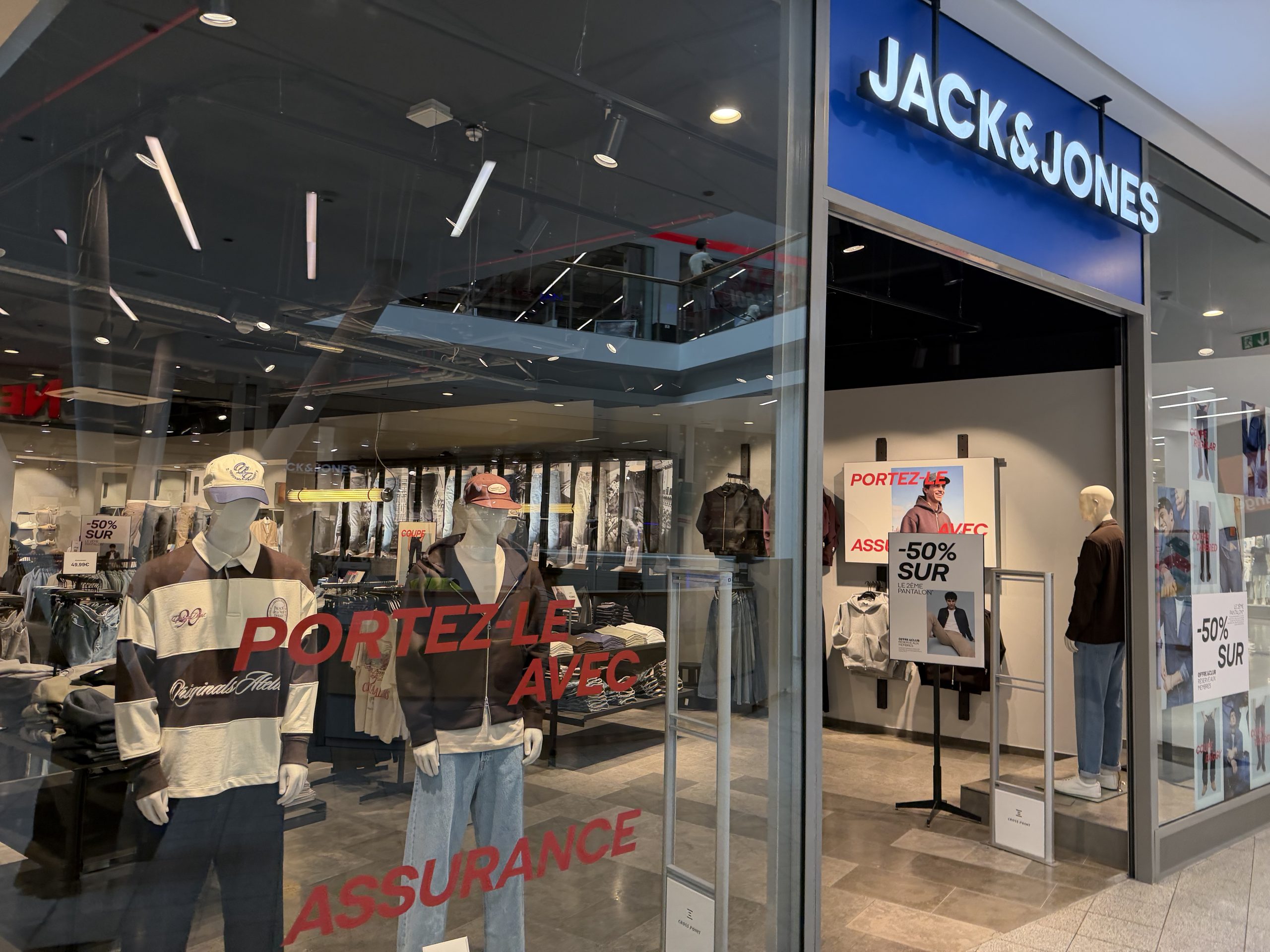The Jack & Jones shopfront in Belval Plaza, with the blue Jack & Jones sign above the entrance and mannequins dressed in rugby shirts, denim jackets and caps in the window.