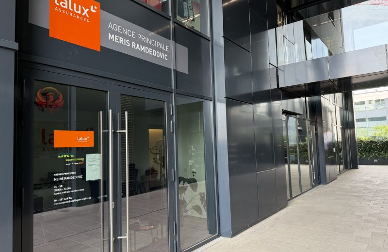 The lalux Assurances agency of Meris Ramdedovic at 9 boulevard du Jazz in Belval, with the orange lalux sign and a door decal listing opening hours and contact details.
