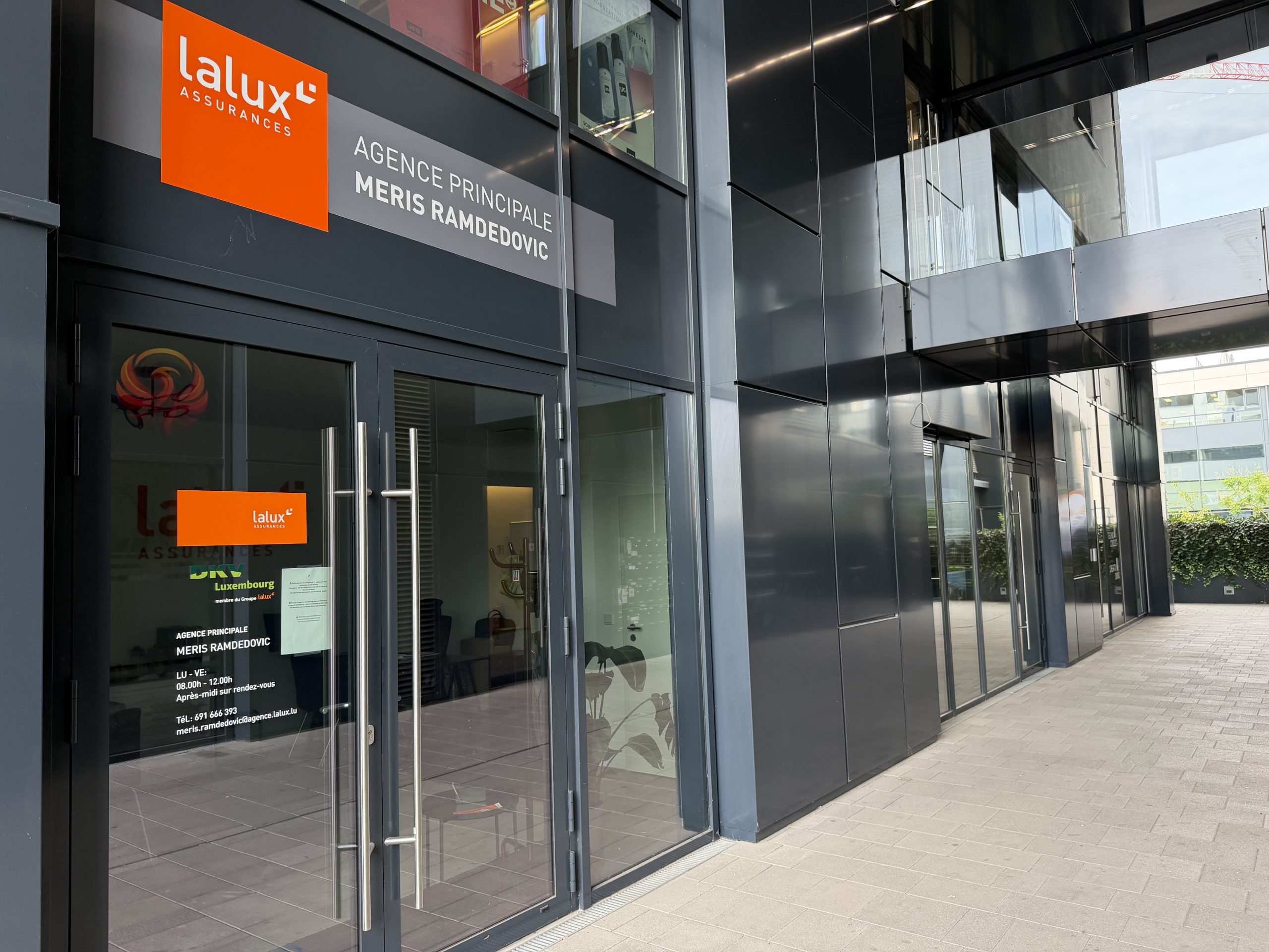 The lalux Assurances agency of Meris Ramdedovic at 9 boulevard du Jazz in Belval, with the orange lalux sign and a door decal listing opening hours and contact details.