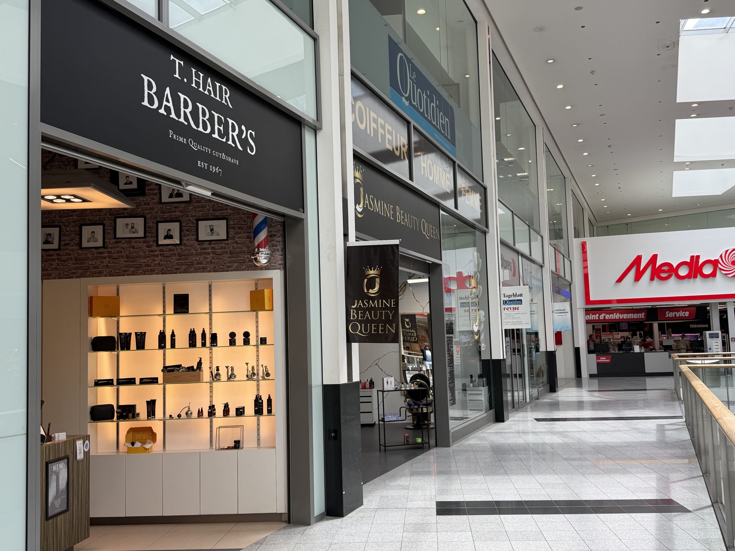 The T. Hair Barber's shopfront at Belval Plaza, dark fascia with the T. Hair Barber's lettering above the entrance.