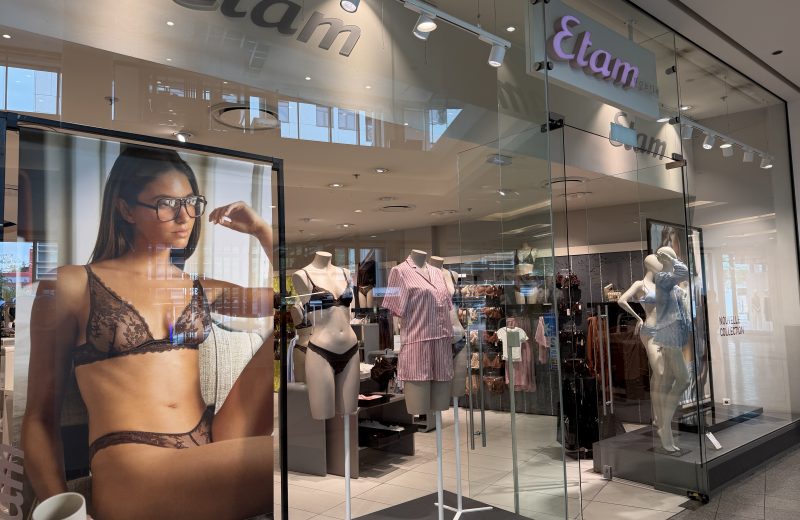 The Etam shopfront in Belval Plaza, with a large window photograph of a model in lace lingerie beside the entrance and mannequins dressed in striped pyjamas and lace tops inside.