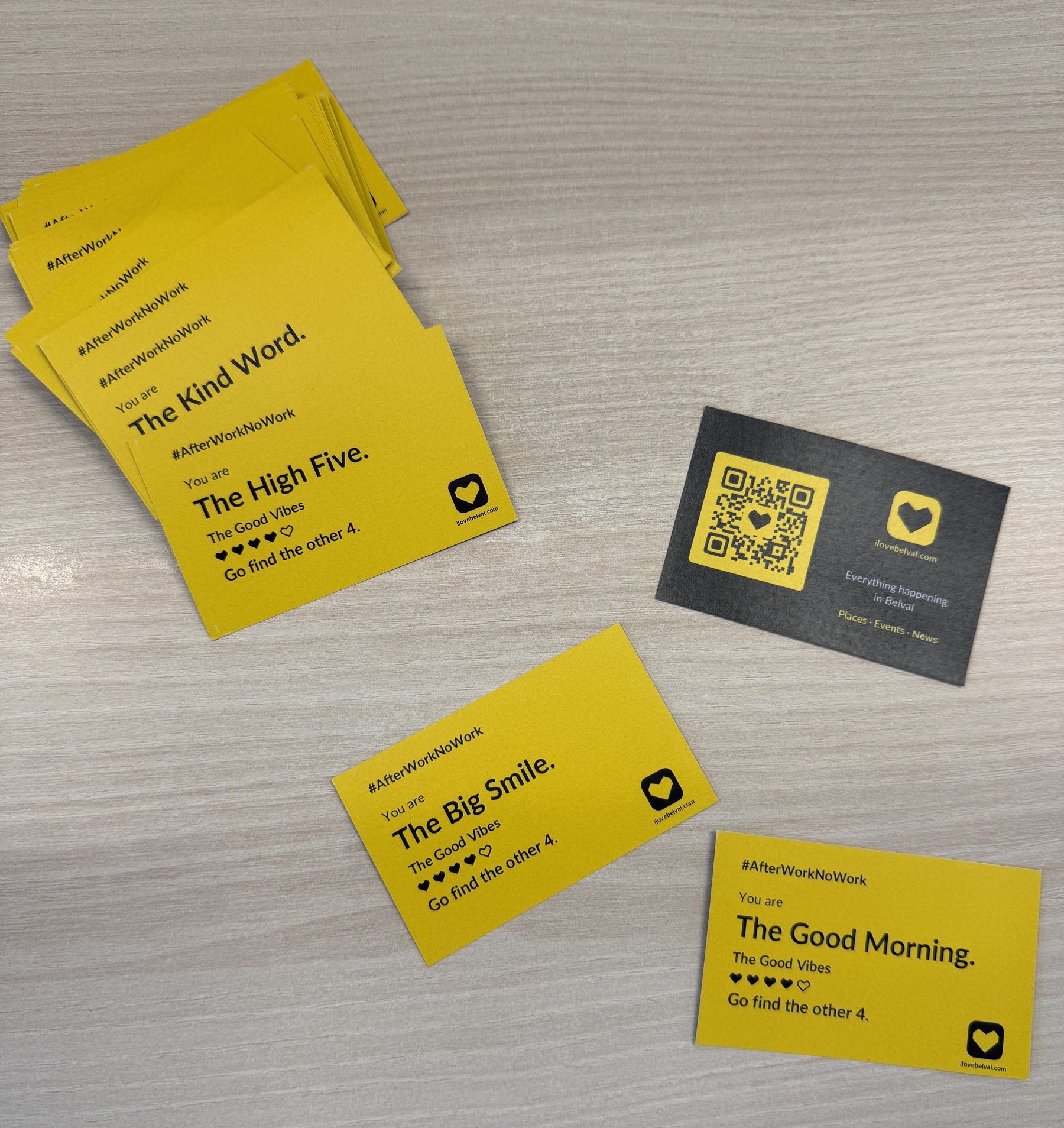 Icebreaker cards on a table, four of them face up reading The Kind Word, The High Five, The Big Smile and The Good Morning, with one turned over to show the black back and its QR code.