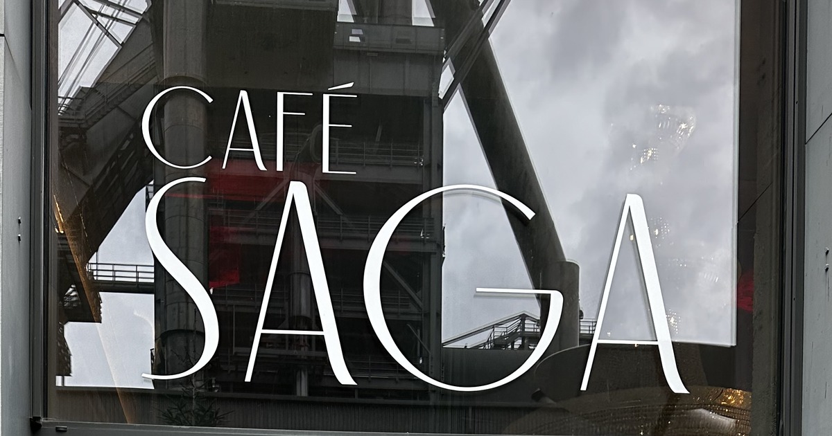 The Café Saga sign on the glass front, with the Belval blast furnace reflected in the window.