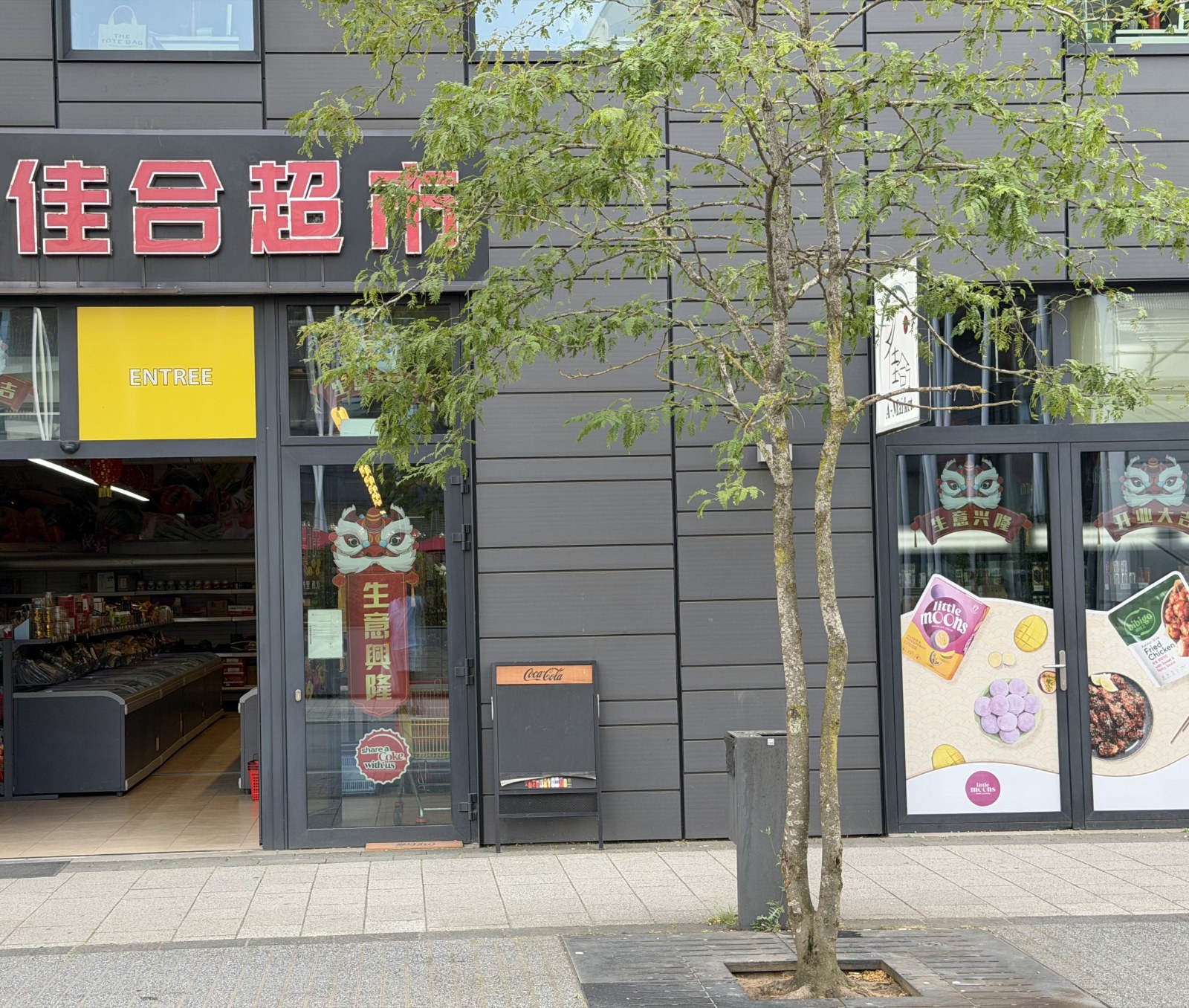 The A-Market Asian supermarket on avenue du Swing in Belval, its red Chinese lettering and A-Market sign above an open entrance, with chest freezers and shelves visible inside.