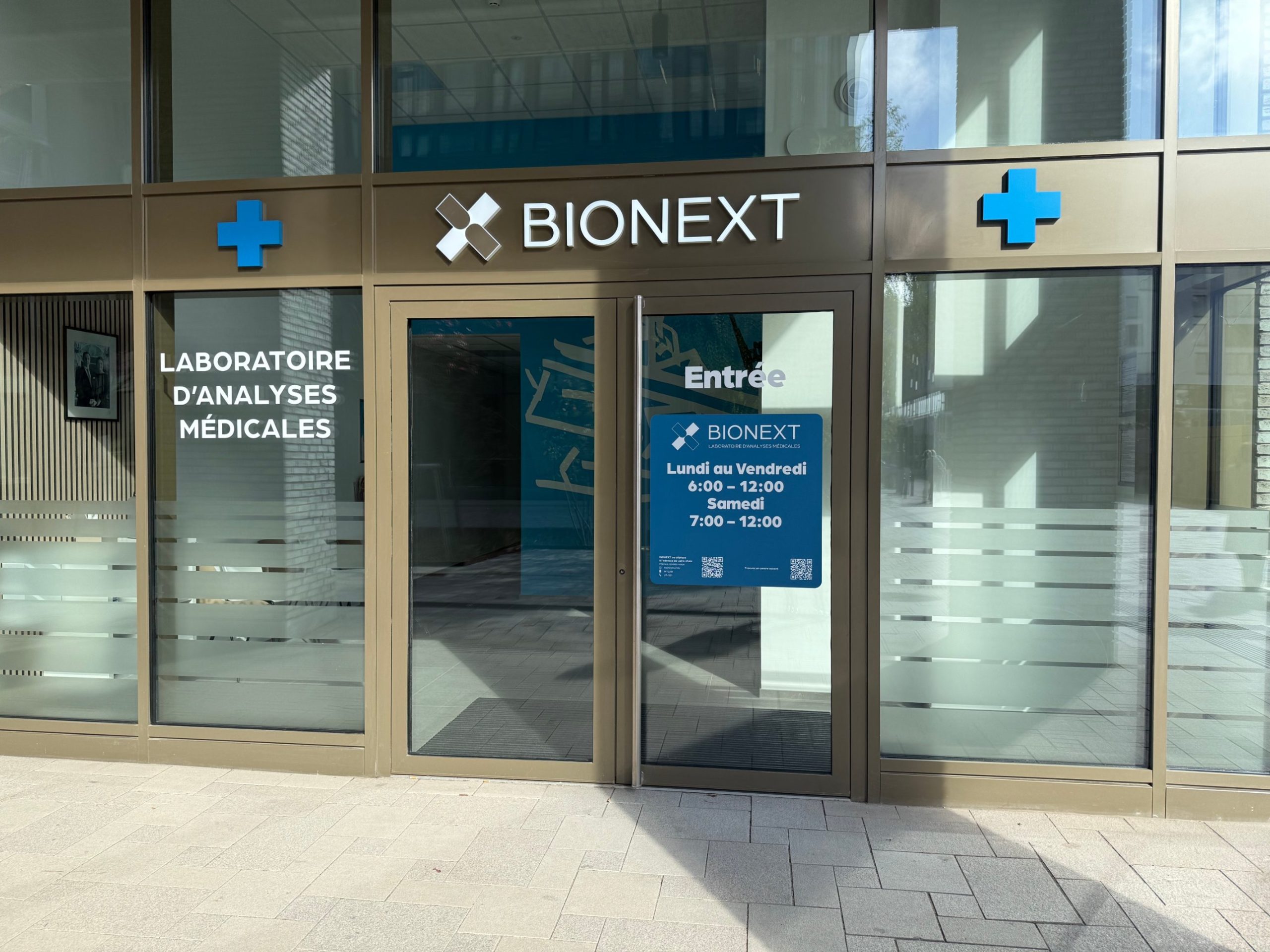 The entrance to the BIONEXT laboratory in Belval, with the opening hours on a blue sign beside the door.