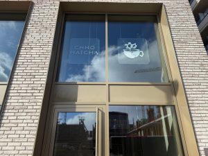 The frosted window of Chno Matcha in Belvaux, with the wordmark and a logo of a cup below a molecule.