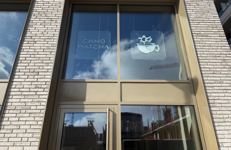 The frosted window of Chno Matcha in Belvaux, with the wordmark and a logo of a cup below a molecule.