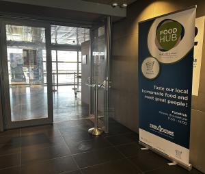 The Food Hub entrance in the Terres Rouges building, a roll-up banner beside the open doors giving the name, the Restopolis mark and the 11:30 to 14:00 opening hours.
