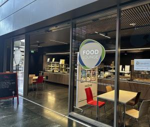 The Food Lounge counter in the Terres Rouges building, the green and blue Food Lounge roundel on the glass with MEET, EAT & STUDY by Restopolis beneath it, and the servery behind.