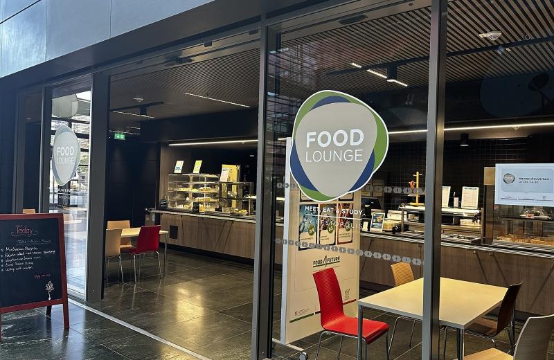 The Food Lounge counter in the Terres Rouges building, the green and blue Food Lounge roundel on the glass with MEET, EAT & STUDY by Restopolis beneath it, and the servery behind.