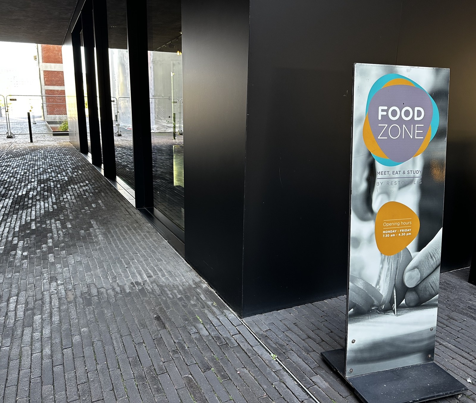 The Food Zone sign on the glazed ground floor of the Maison de l’Innovation on the Belval campus, giving the Restopolis name and the Monday to Friday opening hours.