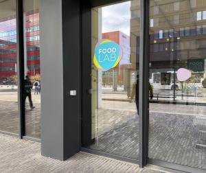 The Food Lab entrance at the Maison des Sciences Humaines, the pink, cyan and yellow Food Lab roundel on the glass door with MEET, EAT & STUDY by Restopolis beneath it.