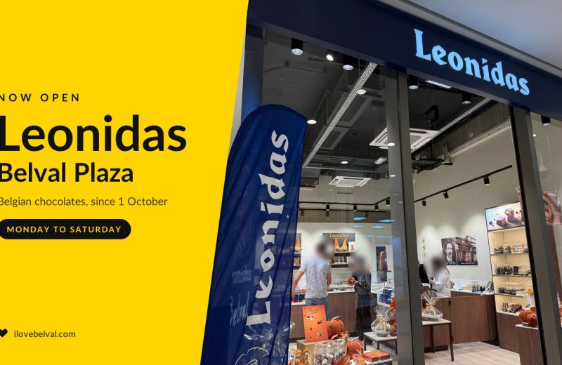 The Leonidas shopfront at Belval Plaza, its name lit on a navy fascia and an autumn window display, beside a yellow I Love Belval panel reading Now open, Leonidas, Belval Plaza.