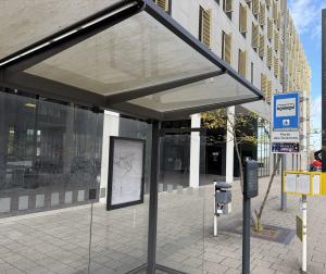 The Porte des Sciences bus shelter in Belval, its network map and real-time display beside the stop sign, with the Maison des Sciences Humaines behind.